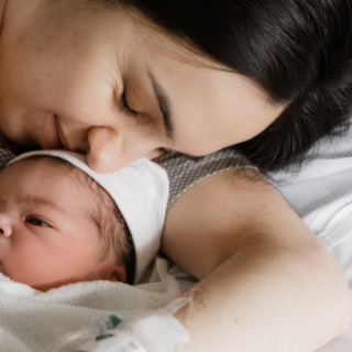 Eine Mama kuschelt nach der Geburt liebevoll mit ihrem Neugeborenen im Kreißsaal